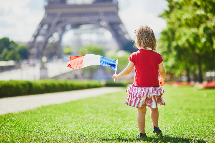 Toddler girl with French national tricolor flag near the Eiffel tower in Paris