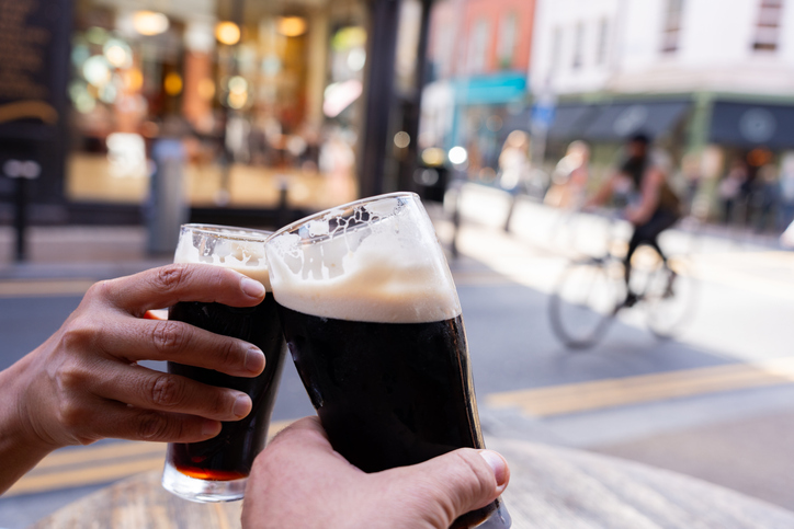 Close-up of two hands toasting each other with Guinness beers