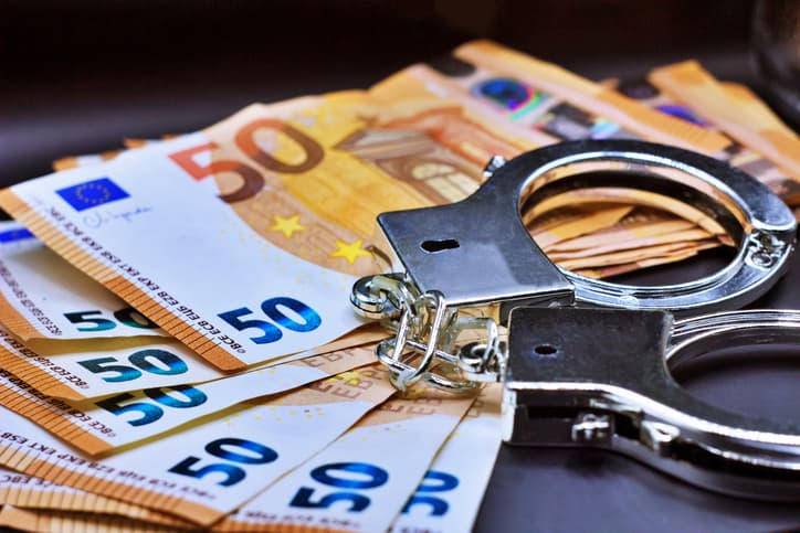 Pair of metal police handcuffs on Euros banknotes money cash background