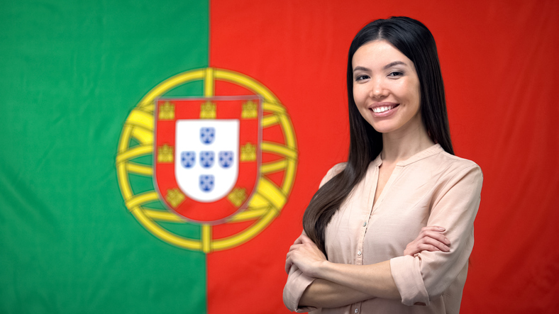 A woman standing infront of the Portugese flag smiling