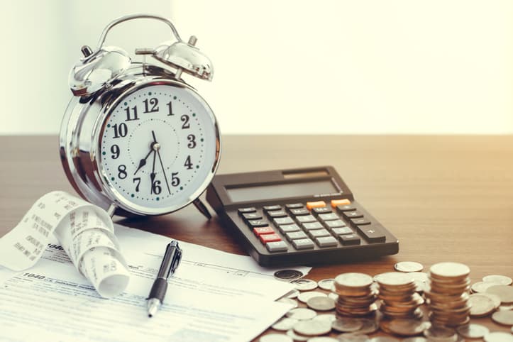 Tax form 1040 with pen, clock,coins and calculator on desk